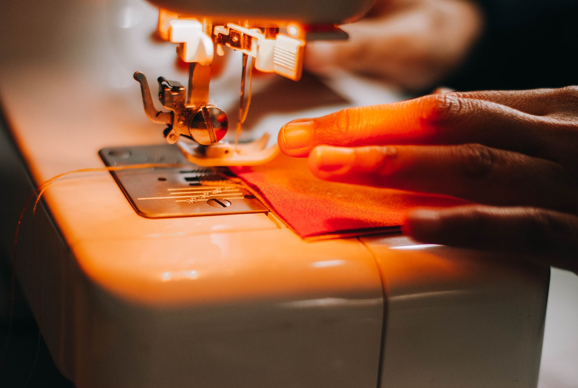 A focused shot of a sewing machine operating with fabric and hand interaction.