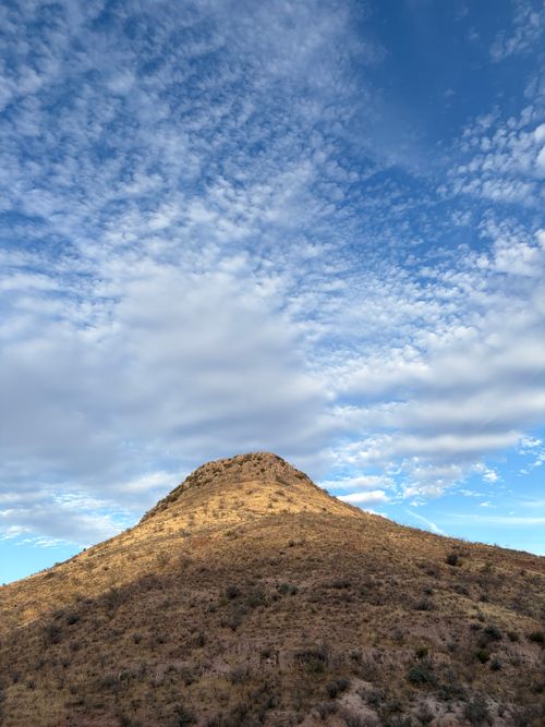 Free A barren hill stands beneath a vast, cloudy sky in Chihuahua, Mexico, capturing the essence of desert tranquility. Stock Photo