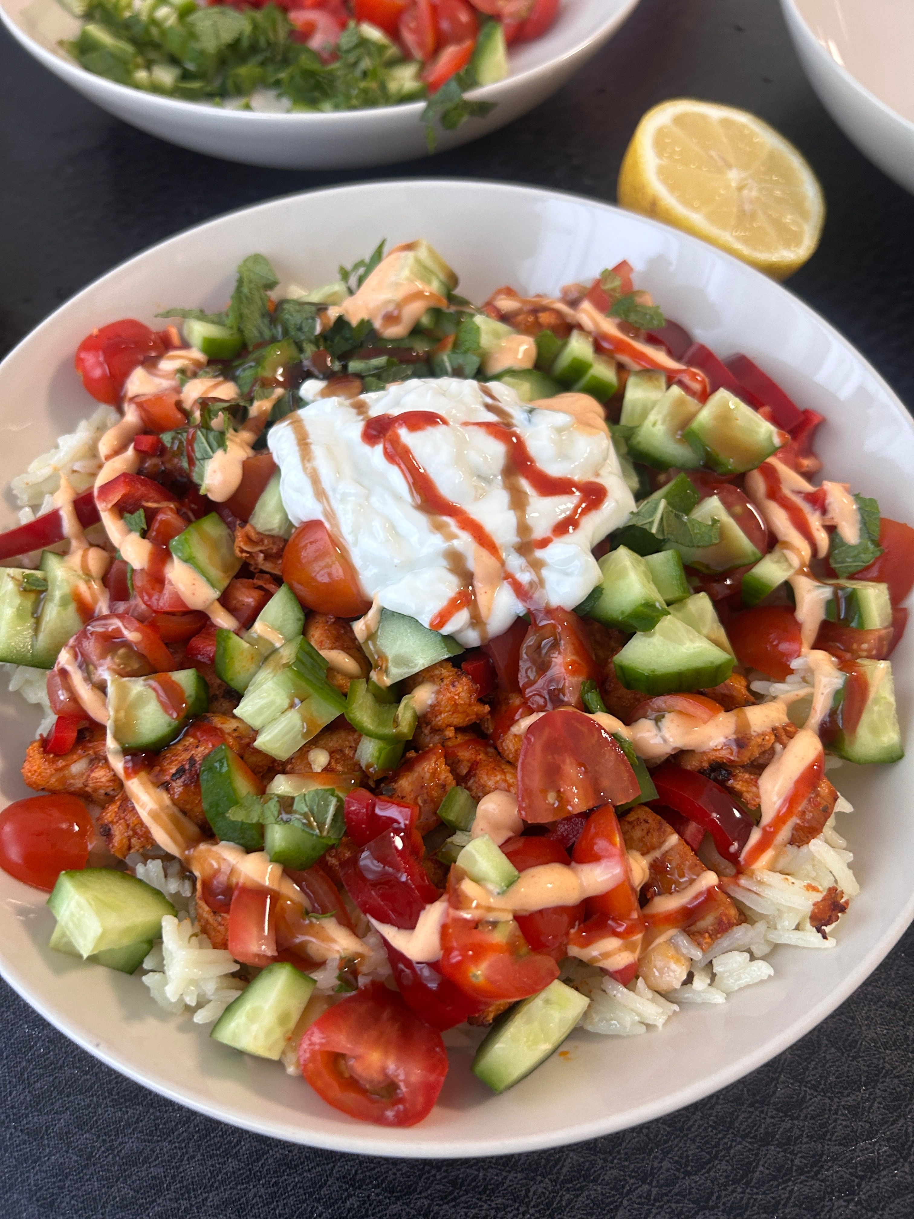 A Mediterranean bowl with vegetables, rice, and yogurt sauce