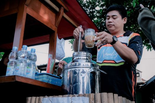 Man at West Java street stall making a traditional Indonesian beverage outdoors. - Fotografer Sidoarjo