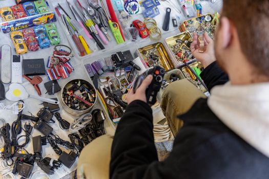 Shopper browsing assorted items at a flea market in Istanbul. A mix of trinkets and gadgets.
