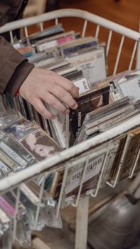 Hand selecting CDs from a vintage music store rack in Istanbul, Türkiye.