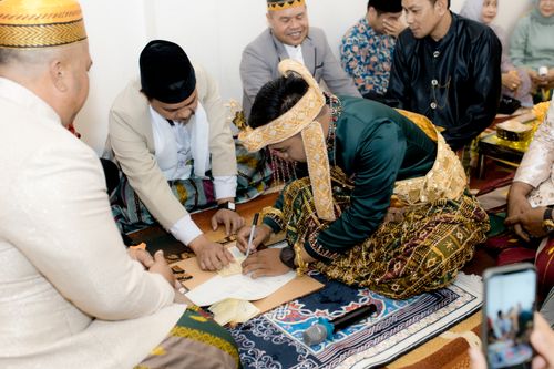 Free Bridegroom signing marriage contract in cultural attire during traditional wedding ceremony. Stock Photo