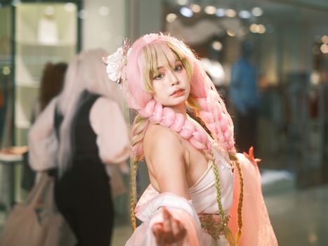 Cosplayer with bright pink hair posing indoors, vibrant and playful.