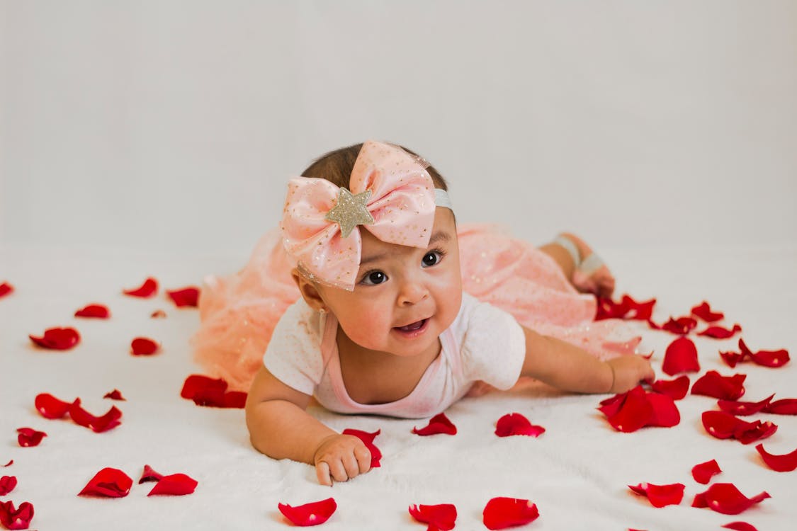 Free Baby In A Dress Lying On Petals Stock Photo