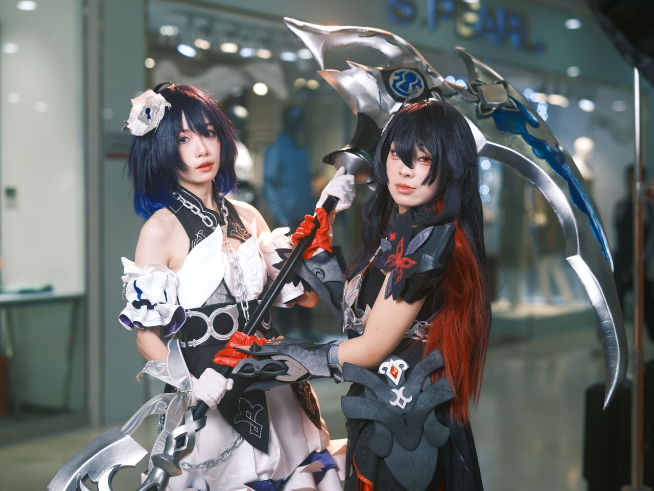 two cosplayers striking a pose with elaborate costumes and weapons in