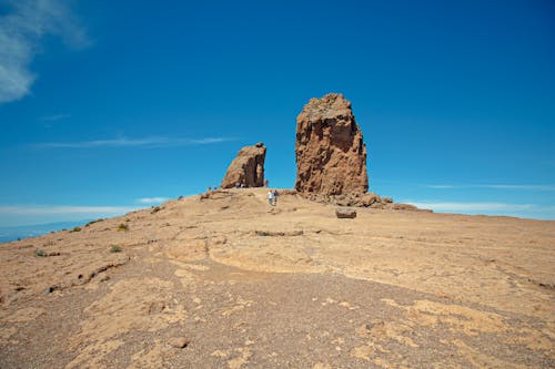 Woman Standing on Brown Mountain Under Blue Sky
