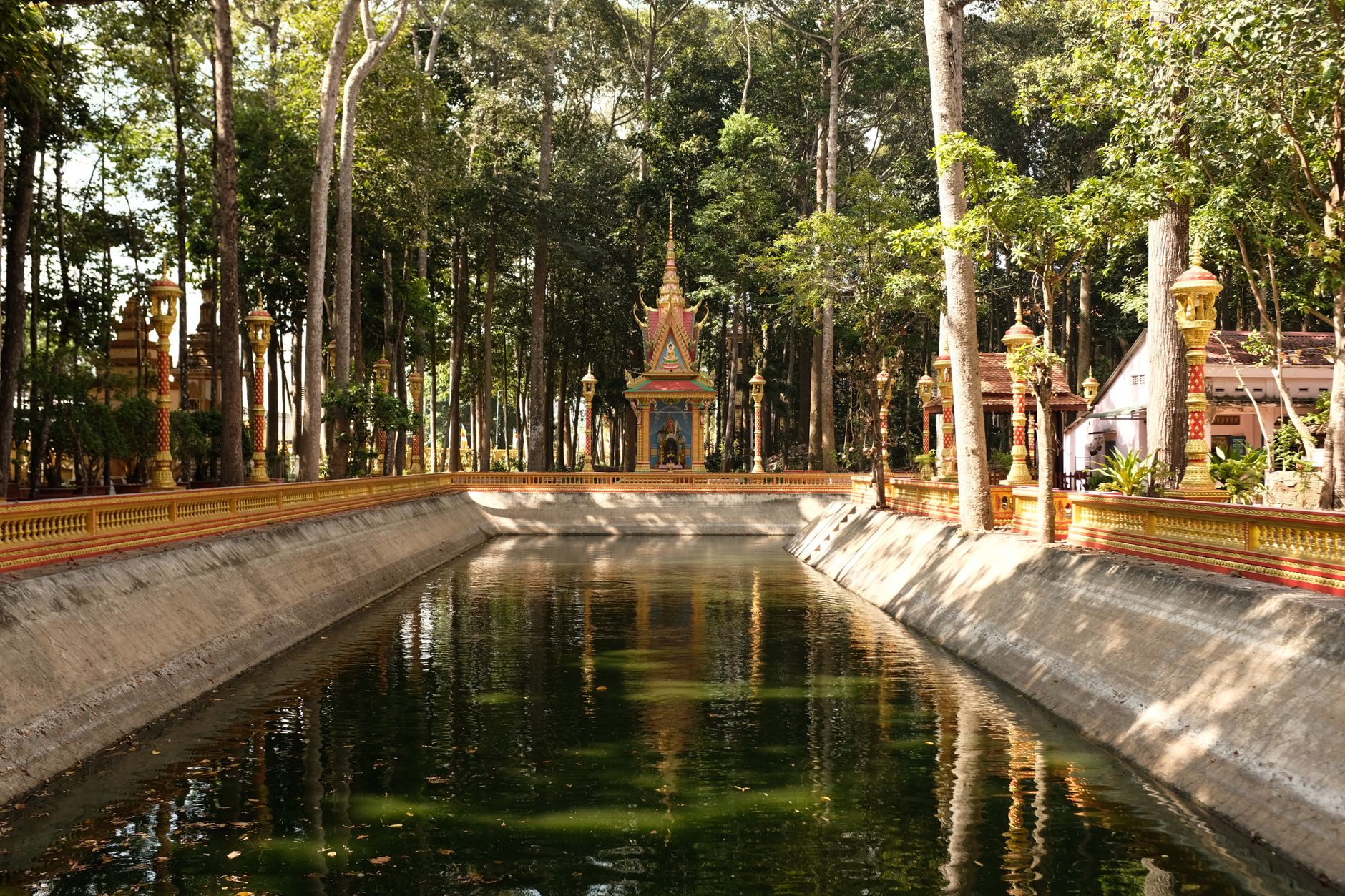 Tranquil scene of a pagoda reflecting in a water canal in Tra Vinh, Vietnam's lush forest.