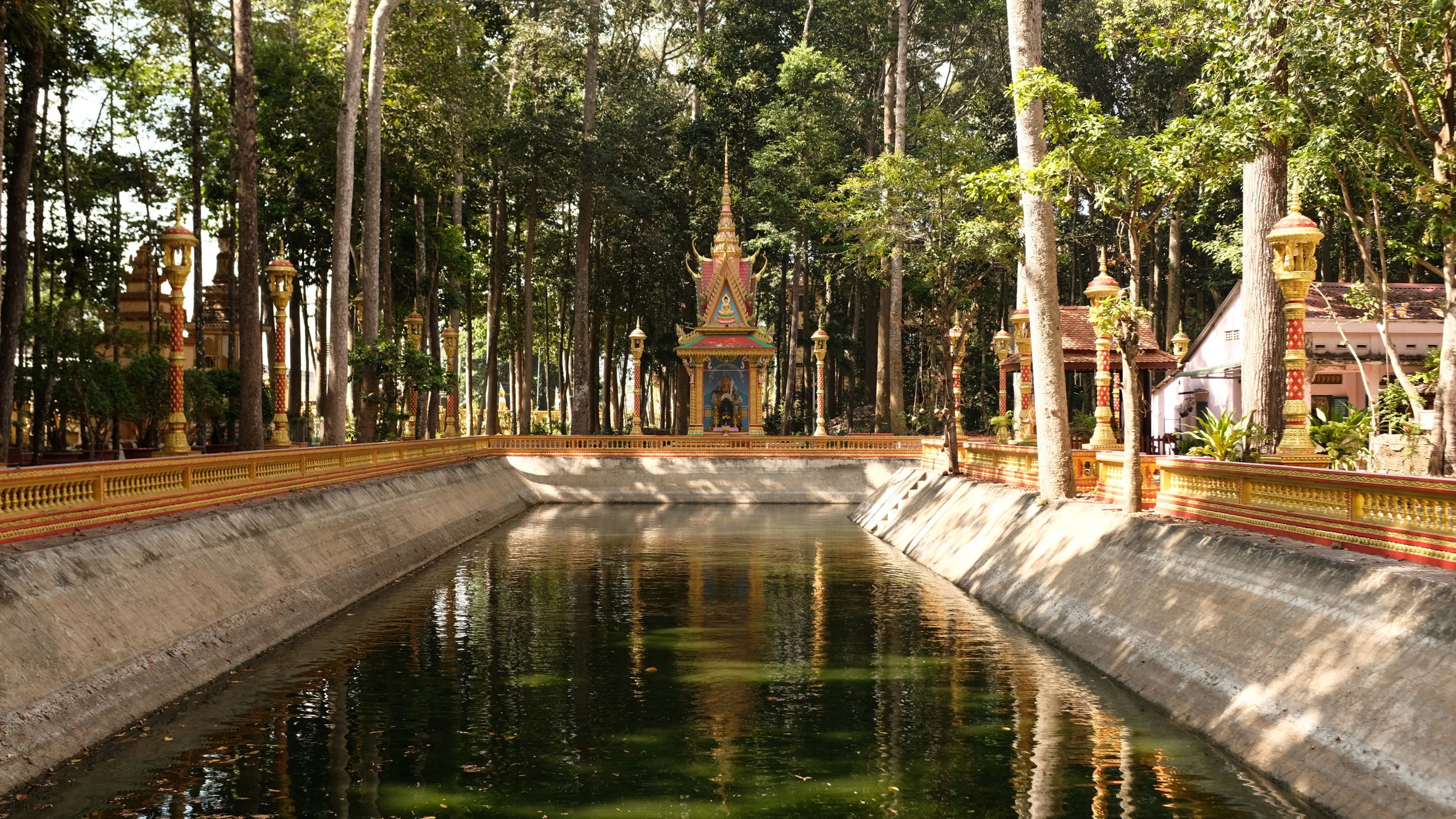 Tranquil scene of a pagoda reflecting in a water canal in Tra Vinh, Vietnam's lush forest.