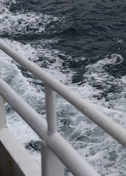 Free Dynamic ocean waves captured from a ship's railing. The powerful sea contrasts with the railing's symmetry. Stock Photo