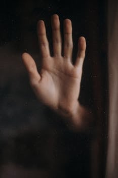 一只张开的人手抵住玻璃窗的特写，营造出分离感