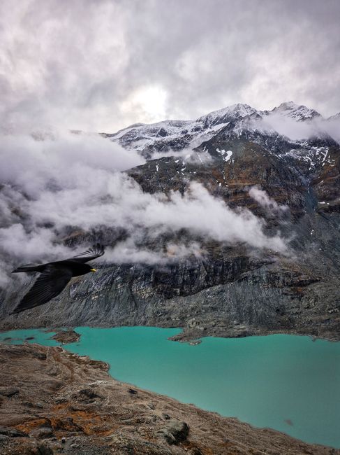 A dramatic view of a lake amid alpine mountains and clouds, captured in Austria.