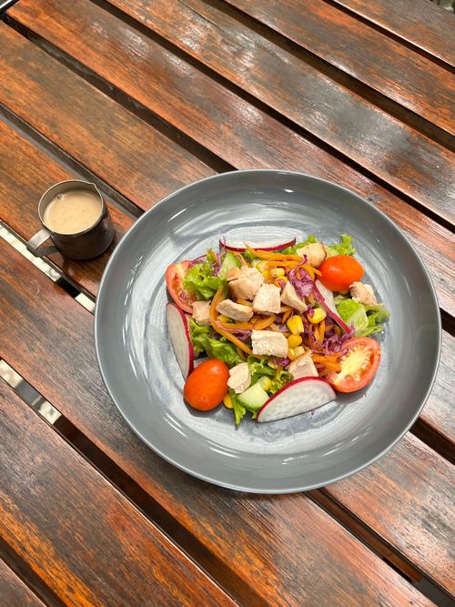Free A vibrant chicken salad with fresh vegetables served on a rustic wooden table in Indonesia. Stock Photo