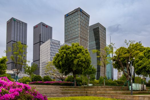 Tall skyscrapers with lush green park and flowers in the foreground, depicting urban nature harmony.