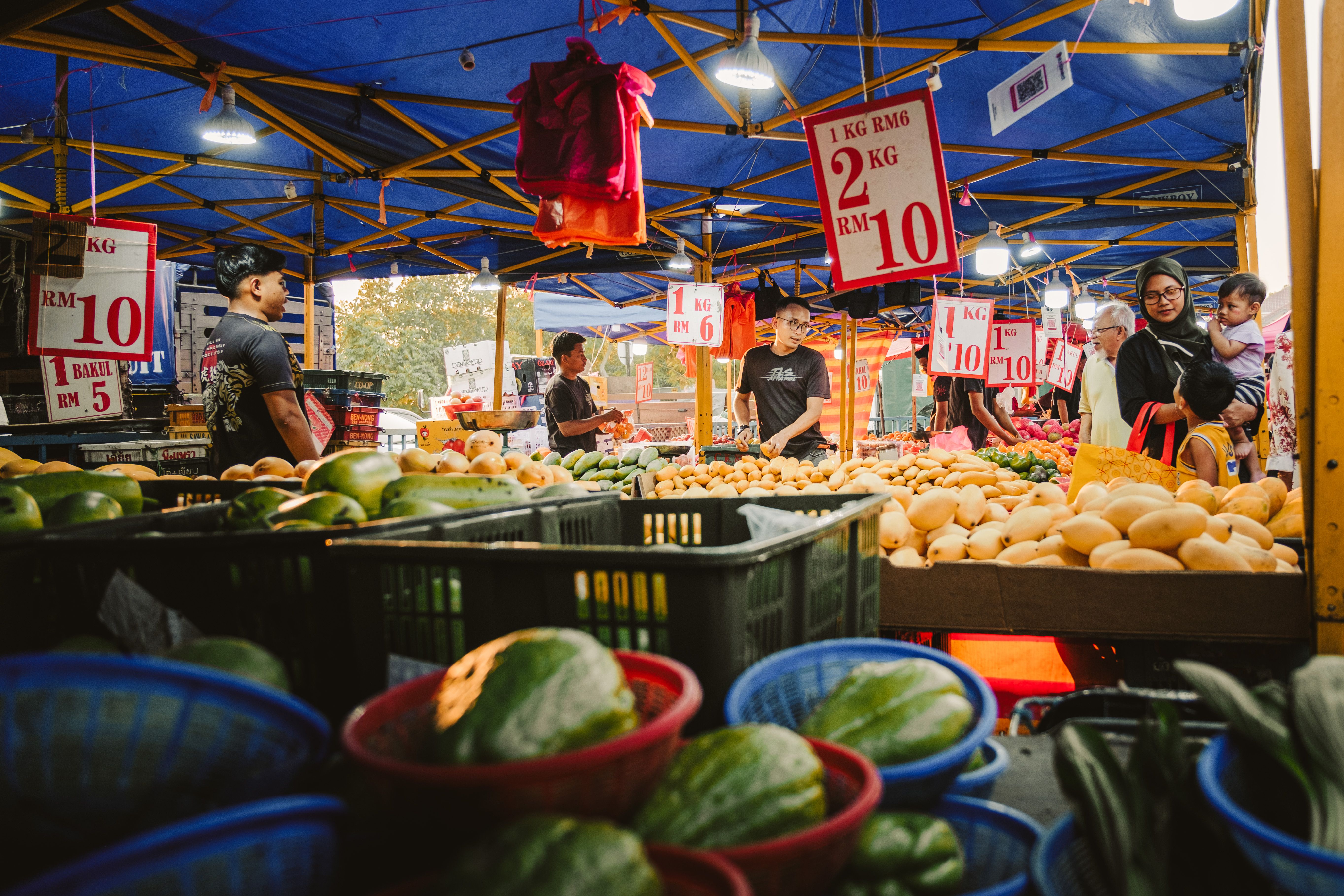 Gratuit Un marché nocturne animé à Sepang, en Malaisie, présentant une variété de produits frais sous des guirlandes lumineuses colorées. Photos