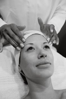 Elegant black and white photo of a woman receiving a relaxing facial massage at a spa.