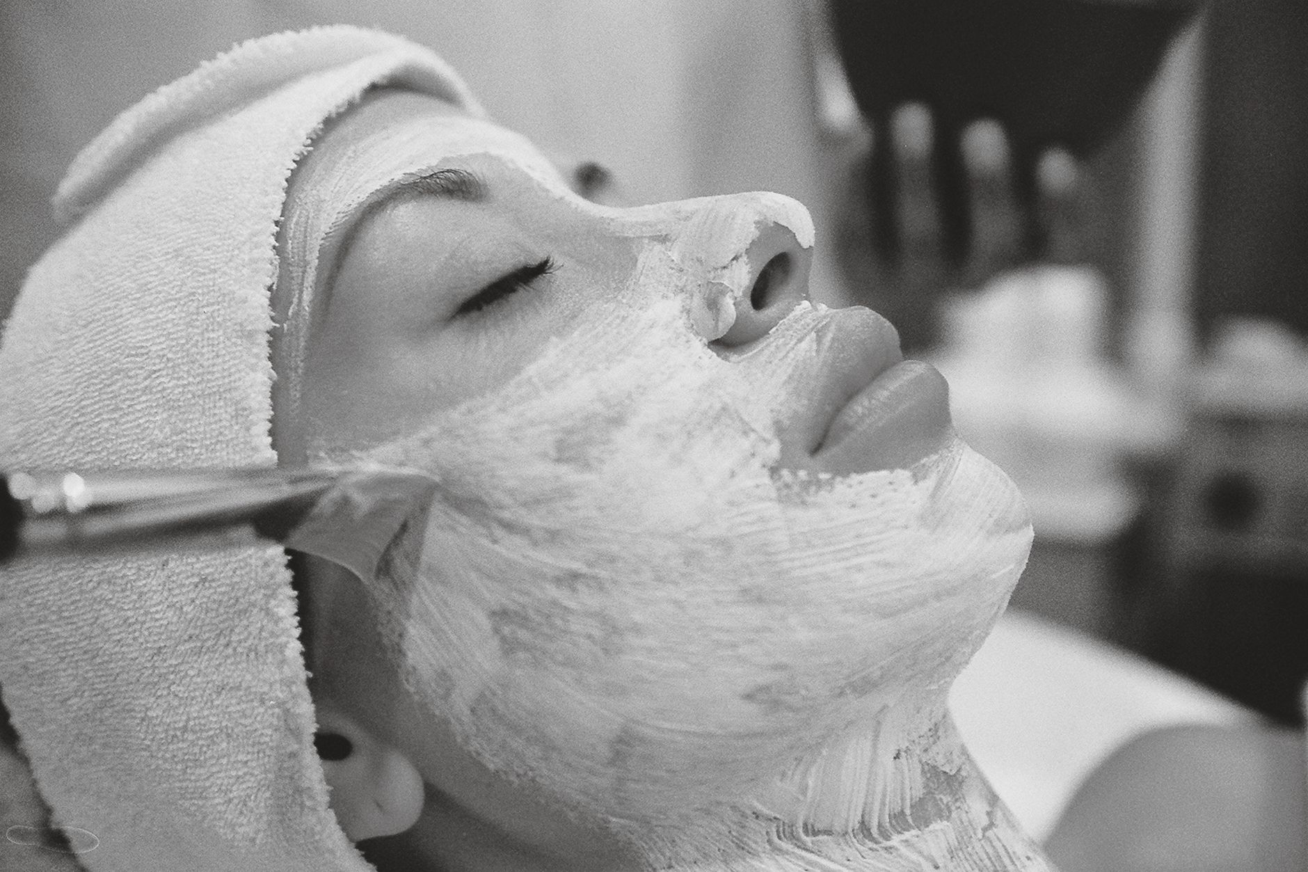 Woman receiving a rejuvenating facial mask treatment at a spa for skincare.