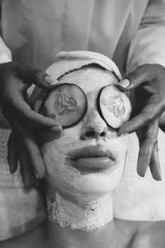 Close-up of a facial spa treatment with cucumber slices on eyes and a face mask.