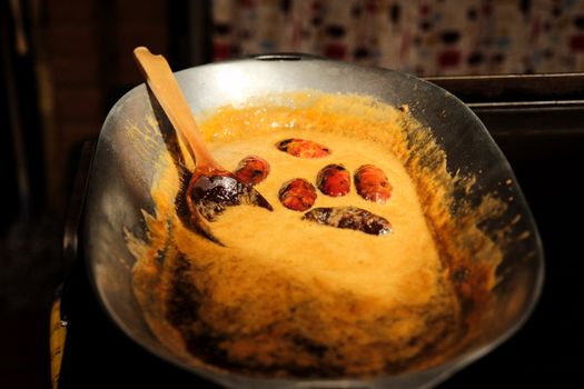Palm oil fruits being cooked in a metal pan, highlighting traditional culinary practices.