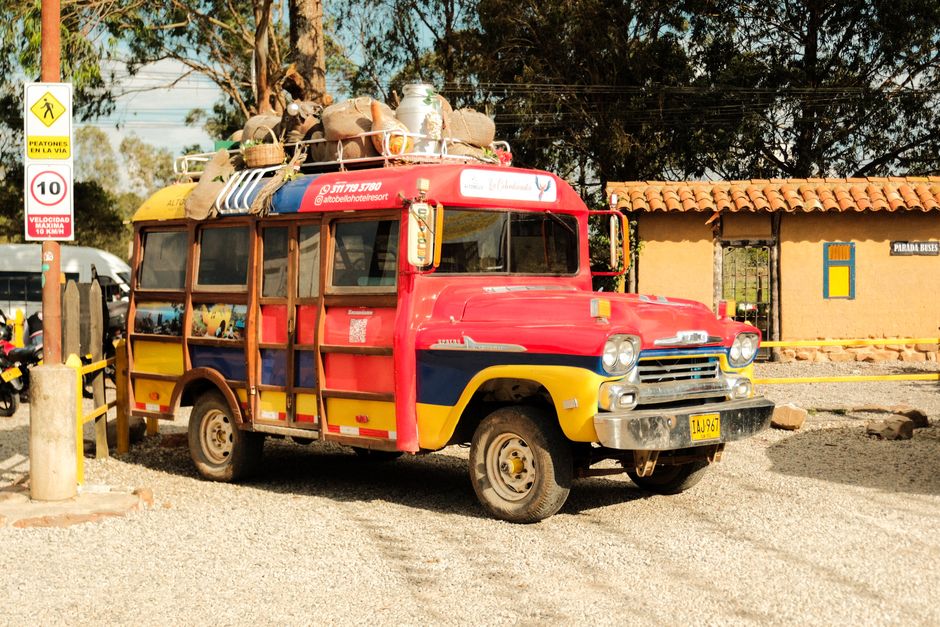 Vibrant Chiva bus parked outdoors, capturing cultural essence with traditional goods on top.