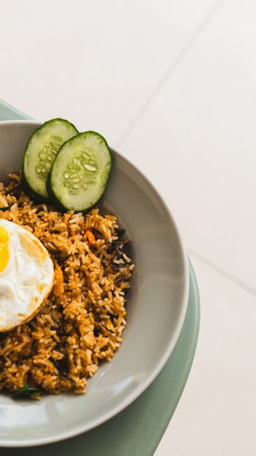 A pile of golden, slightly crisped fried rice with scrambled egg and scallions being tossed on a flat-top griddle.