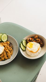 Tantalizing bowls of fried rice topped with sunny-side-up eggs and fresh cucumber slices. - Fotografer Sidoarjo