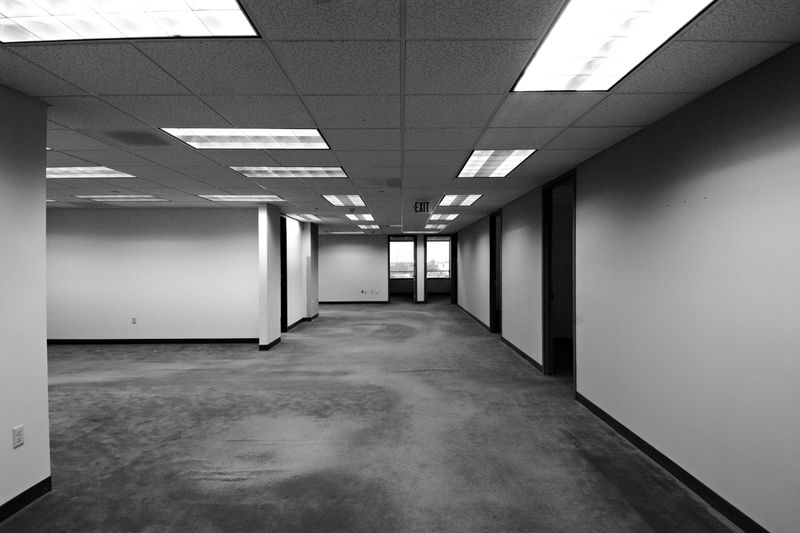 Black and white image of an empty office space with fluorescent lighting