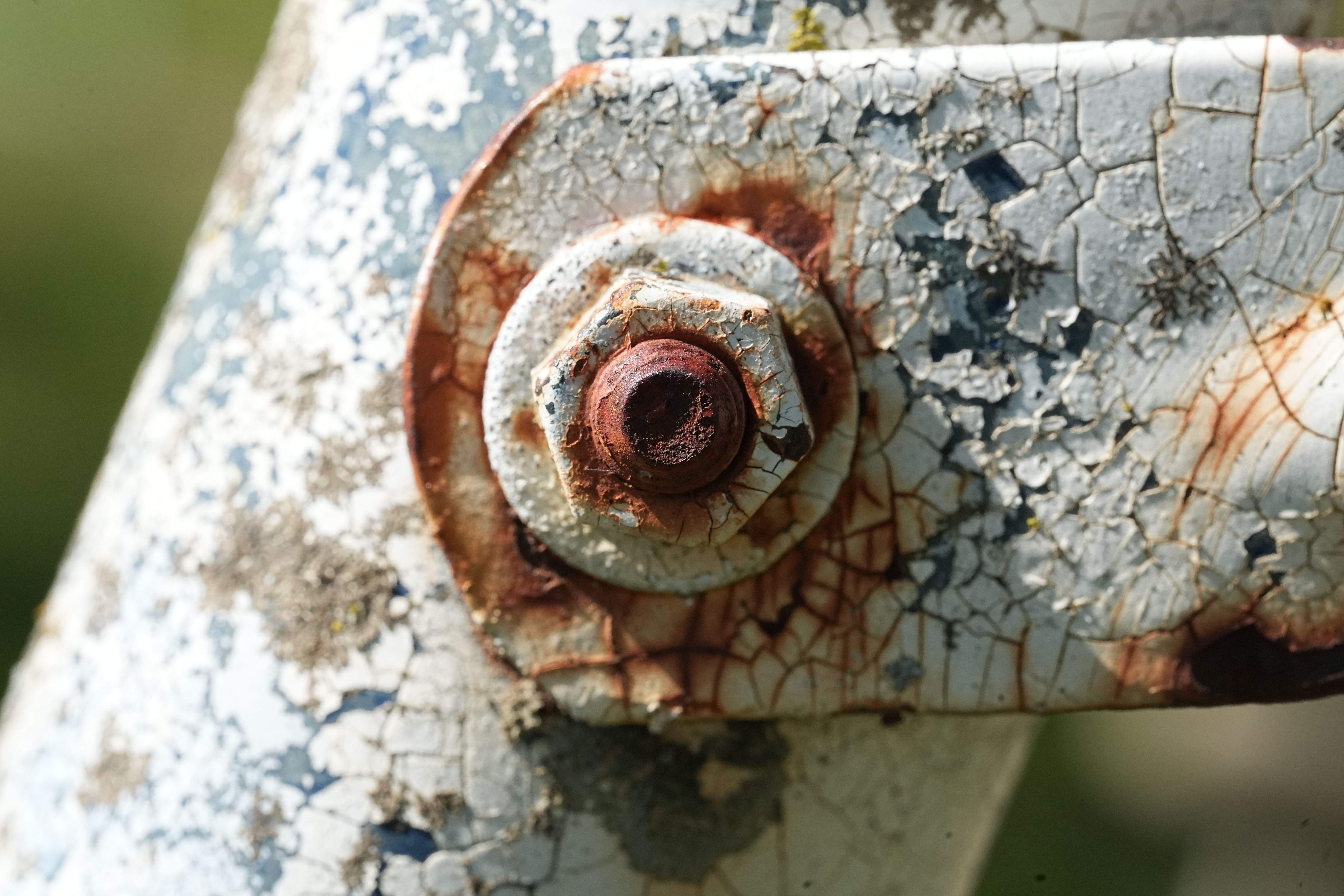 Close up stock photograph of a mechanical bolt and cracked weathered metal surface representing fatigue and durability failure