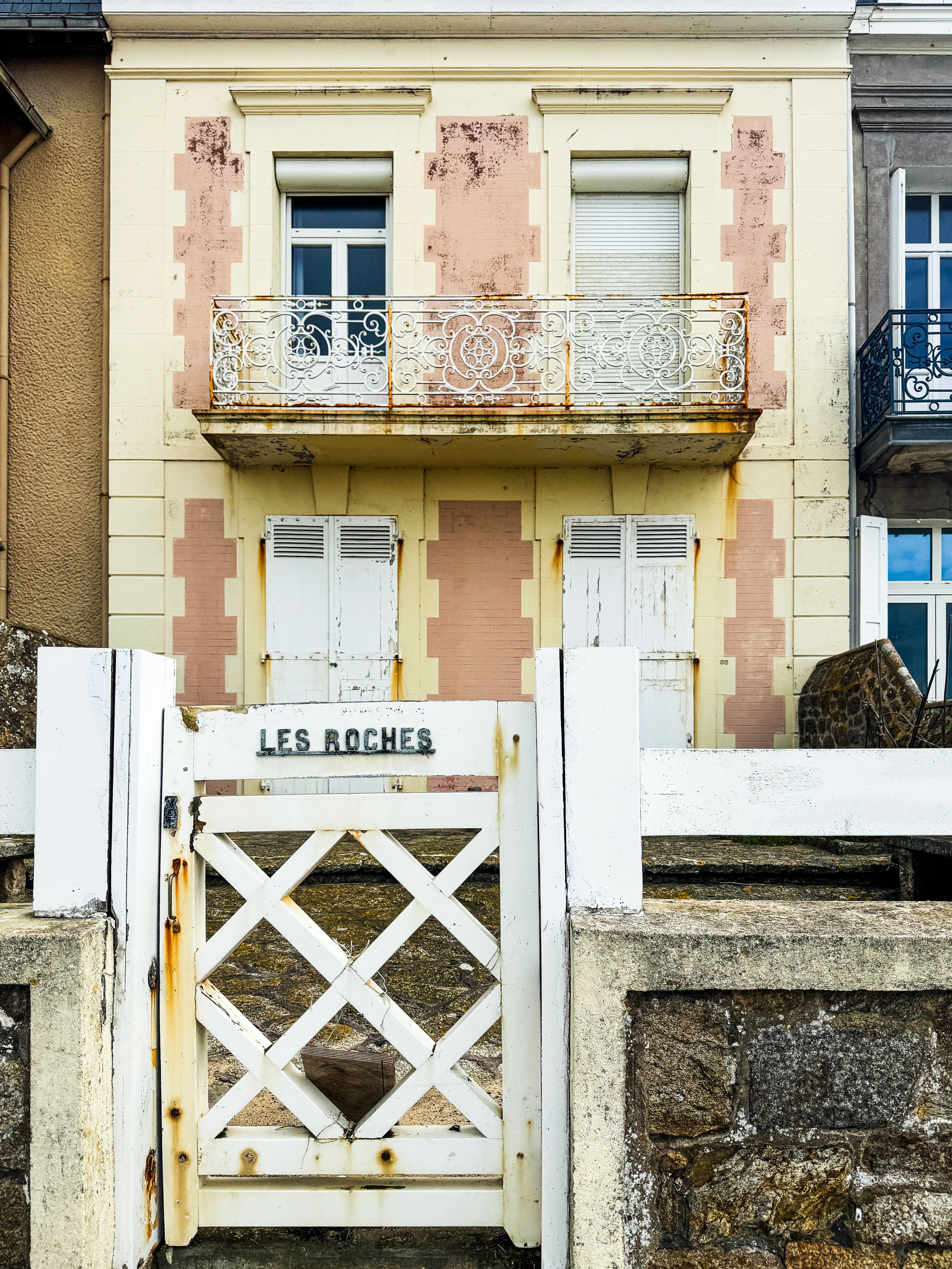 A picturesque French house with a vintage gate labeled 'Les Roches' showcasing classic architecture and coastal charm.