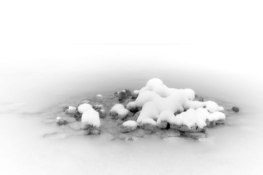 Simplicity of snow-covered rocks creating a minimalist winter scene, emphasizing tranquility and isolation.