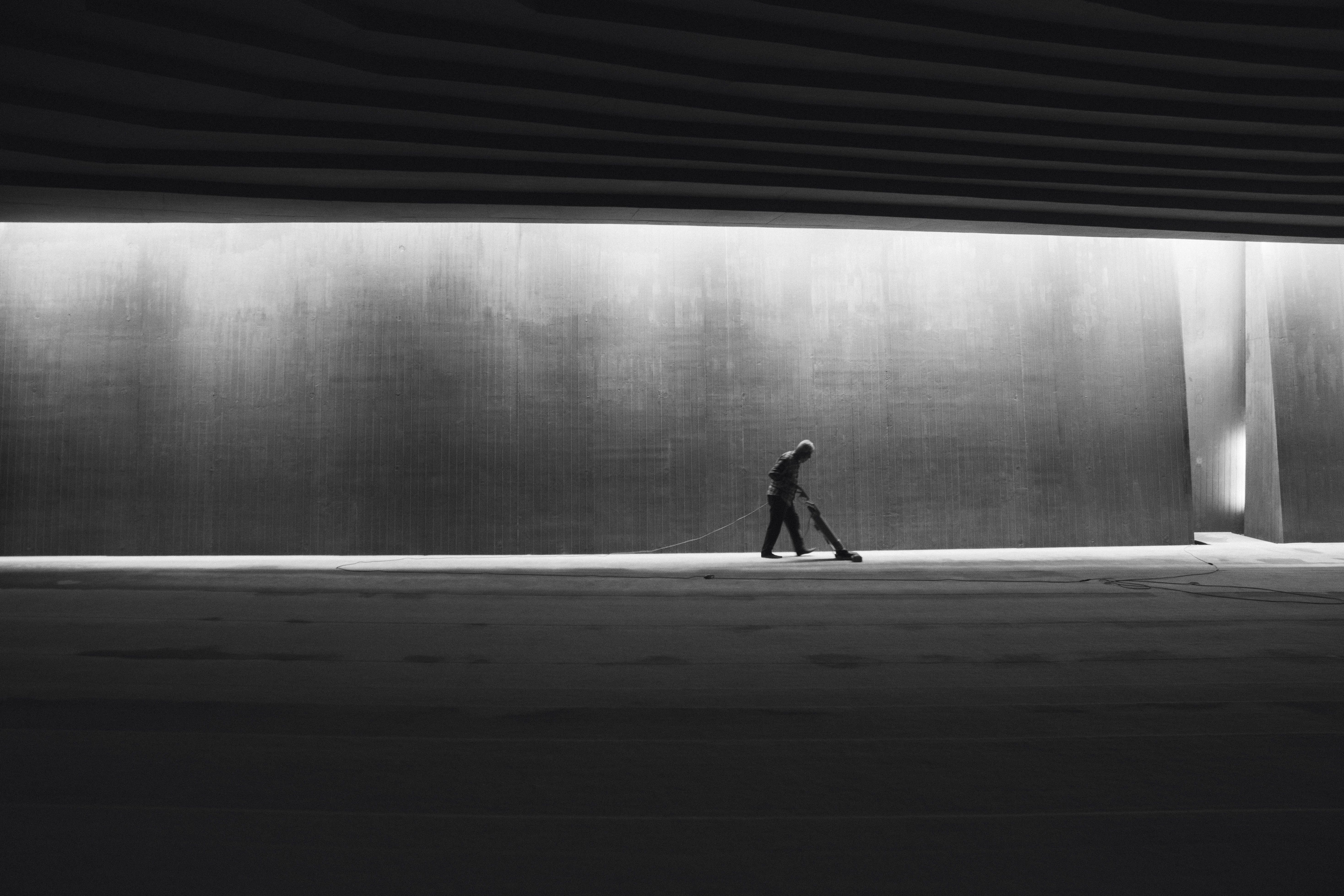 Silhouette of a person cleaning an interior space, showcasing solitude in a modern urban environment.