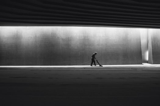 Silhouette of a person cleaning an interior space, showcasing solitude in a modern urban environment.