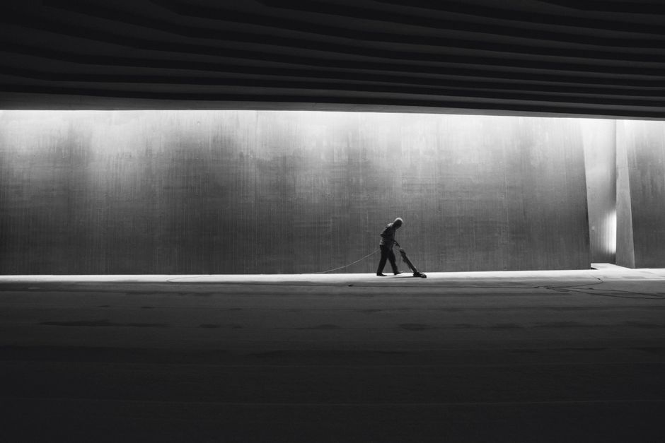 Silhouette of a person cleaning an interior space, showcasing solitude in a modern urban environment.