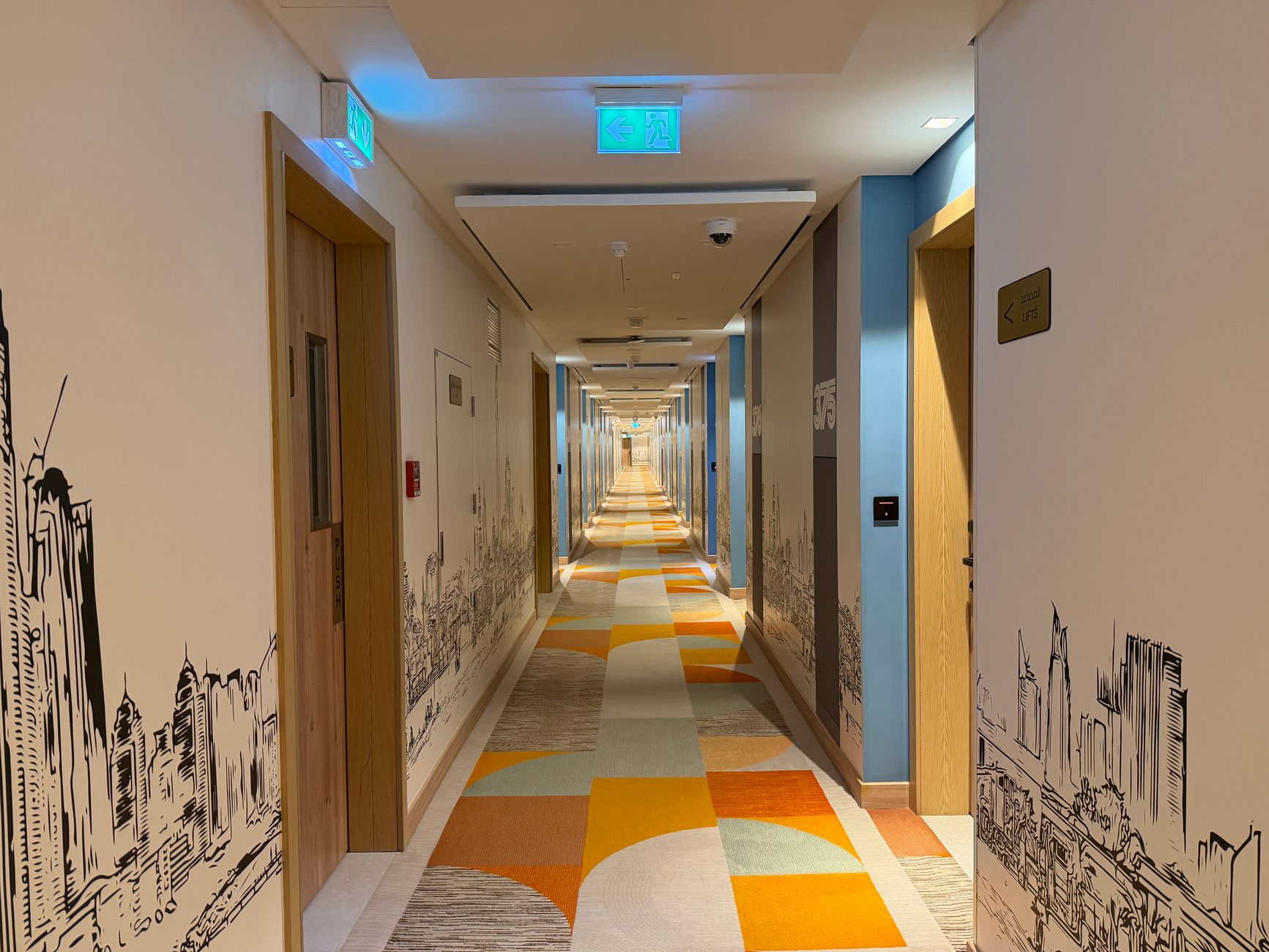 A fire door in a hospital corridor with a digital screen above it showing an inspection schedule.