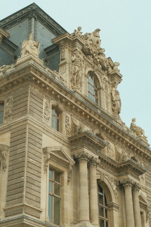 Free Classic architectural details of the Louvre Museum in Paris, France showcasing ornate sculptures and columns. Stock Photo
