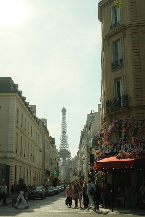 Free Charming Paris street scene with the Eiffel Tower in the background, capturing local architecture. Stock Photo