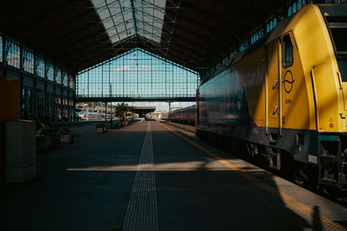 Free A vibrant view of Nyugati Station in Budapest, featuring a yellow train and architectural details. Stock Photo