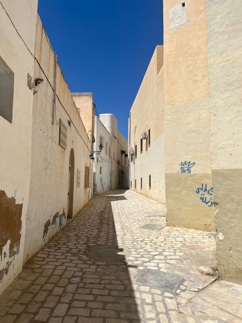 Free A sunlit alley with cobbled stone pavement and traditional buildings in a historic medina. Stock Photo