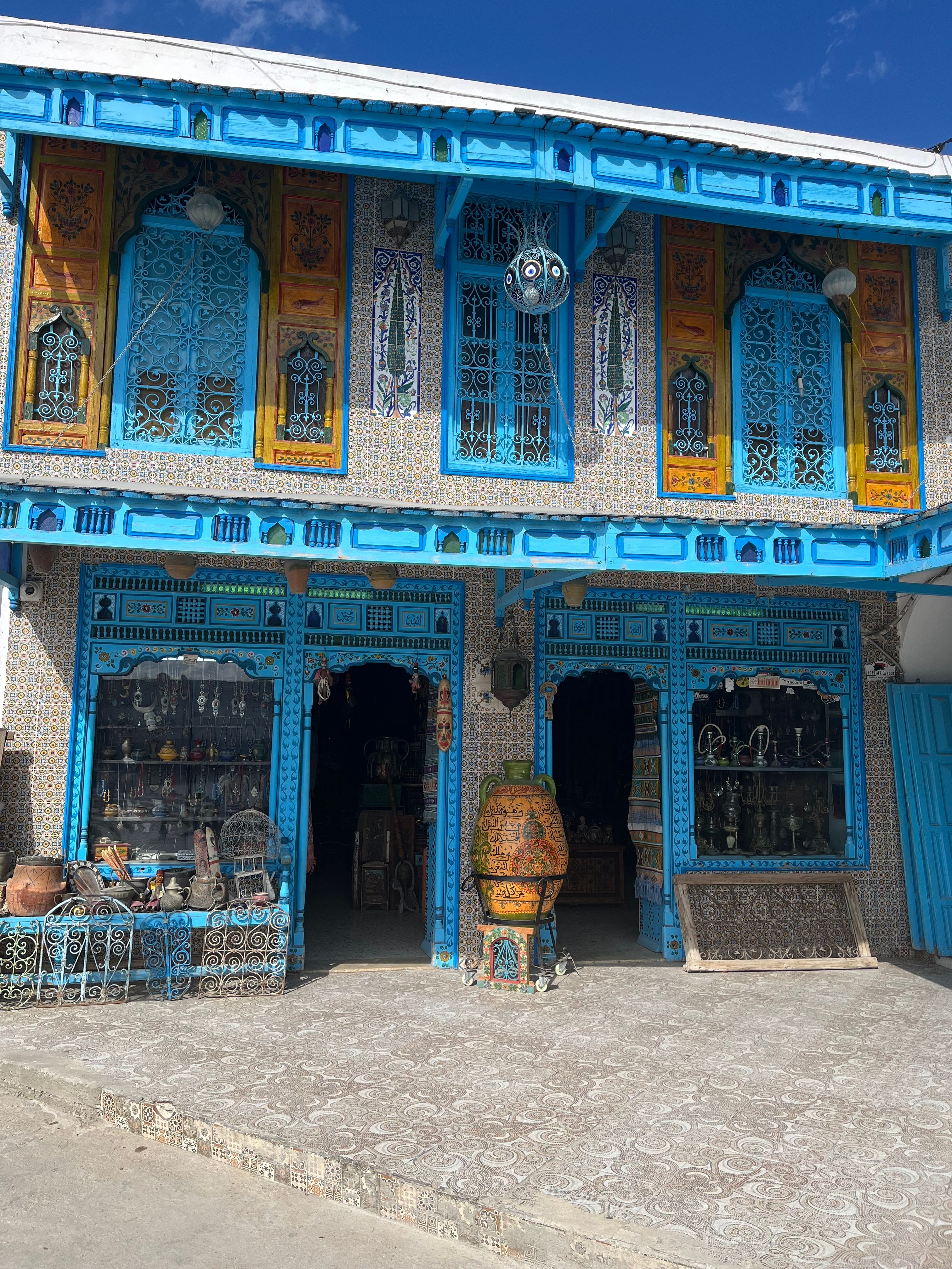Charming Tunisian shop with ornate blue and yellow facade selling traditional crafts.