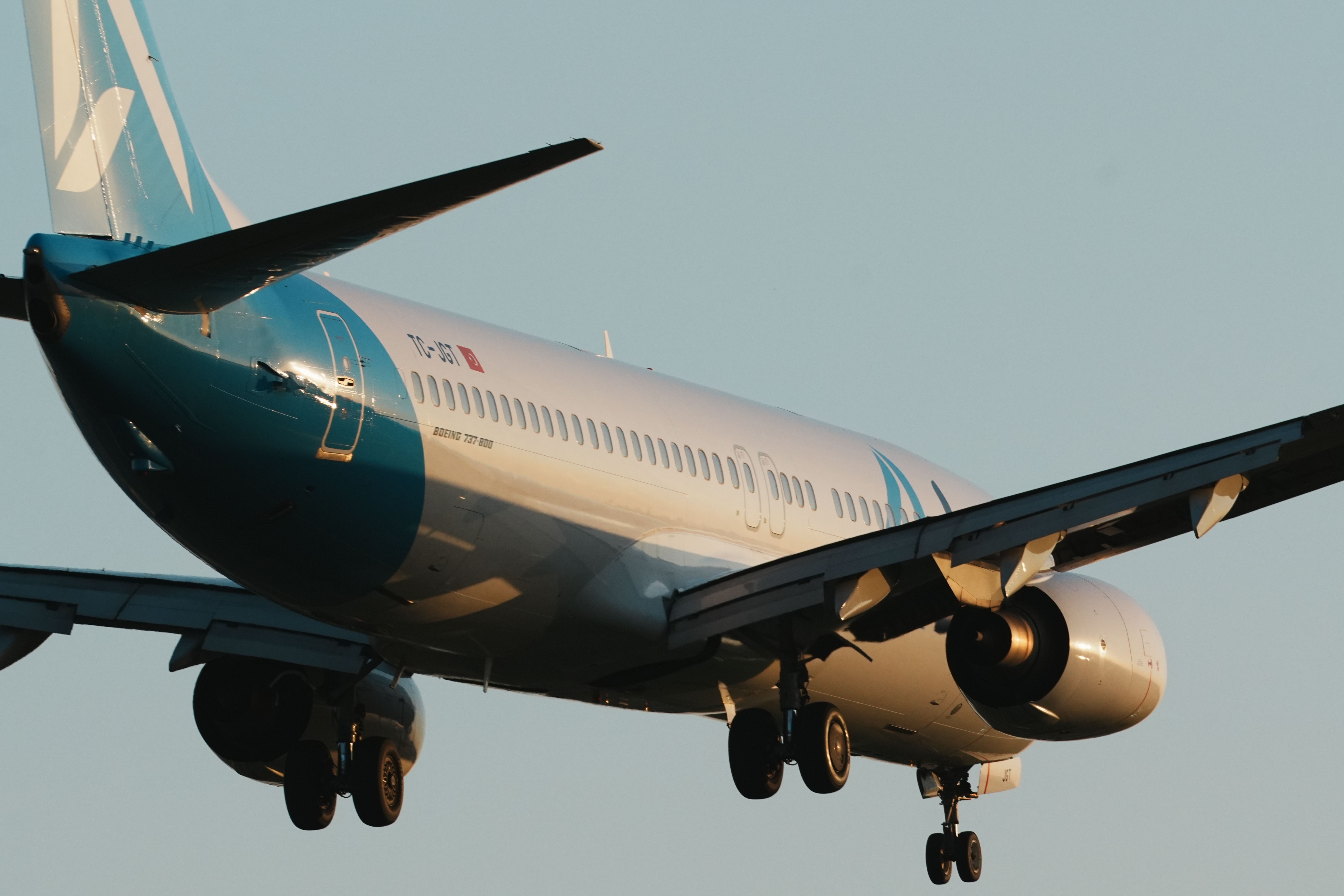 A modern passenger airplane in flight over Istanbul, captured during sunset with a clear sky.