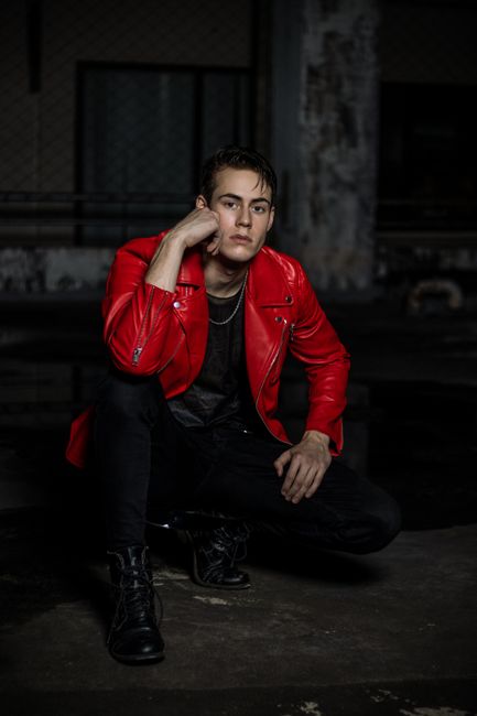 Fashionable male model posing in a striking red jacket during an indoor urban photoshoot.