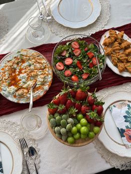 A set dining table with fresh salad, fruits, and appetizers, creating a vibrant and inviting meal.