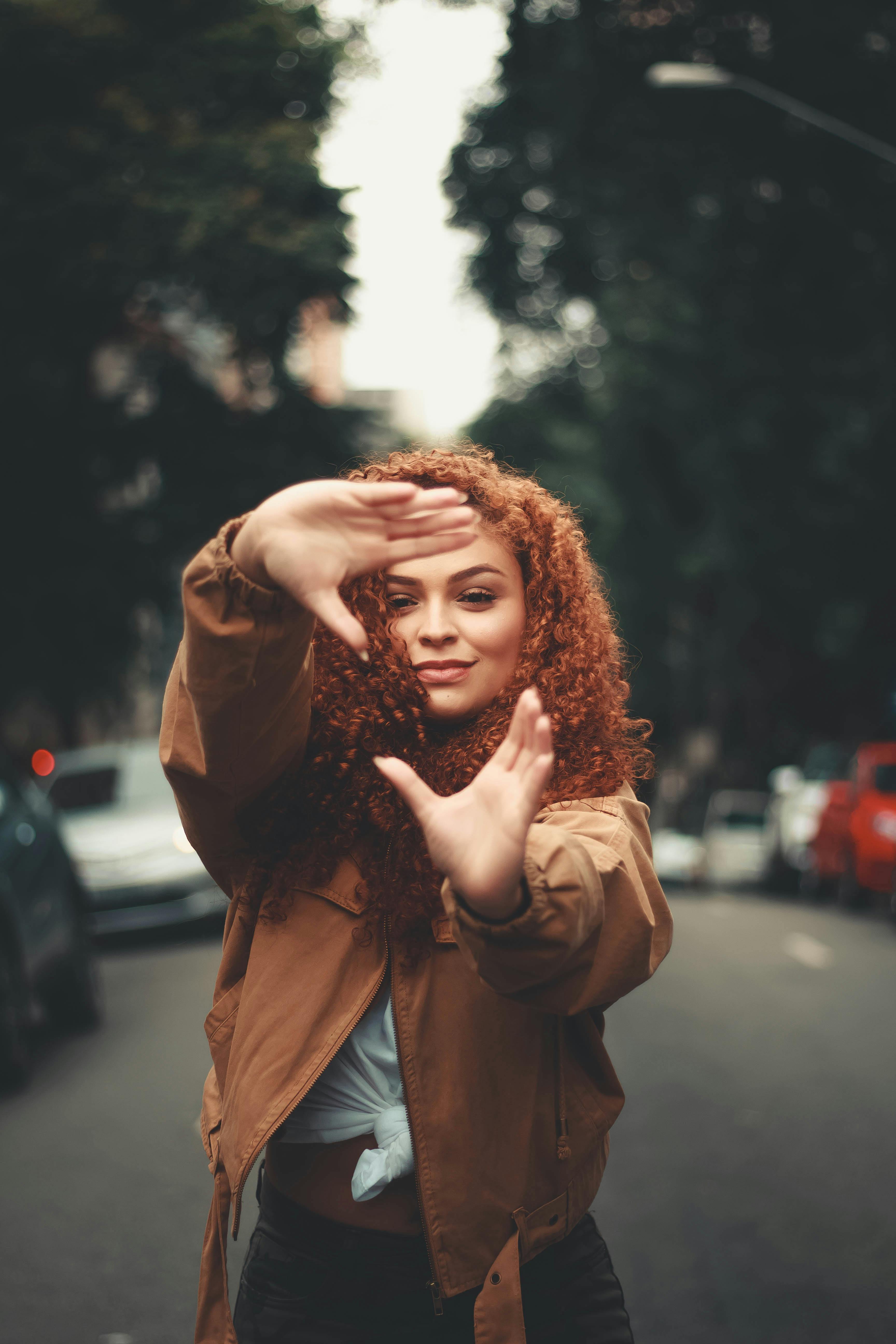 cheerful woman making shape of screen with hands on street