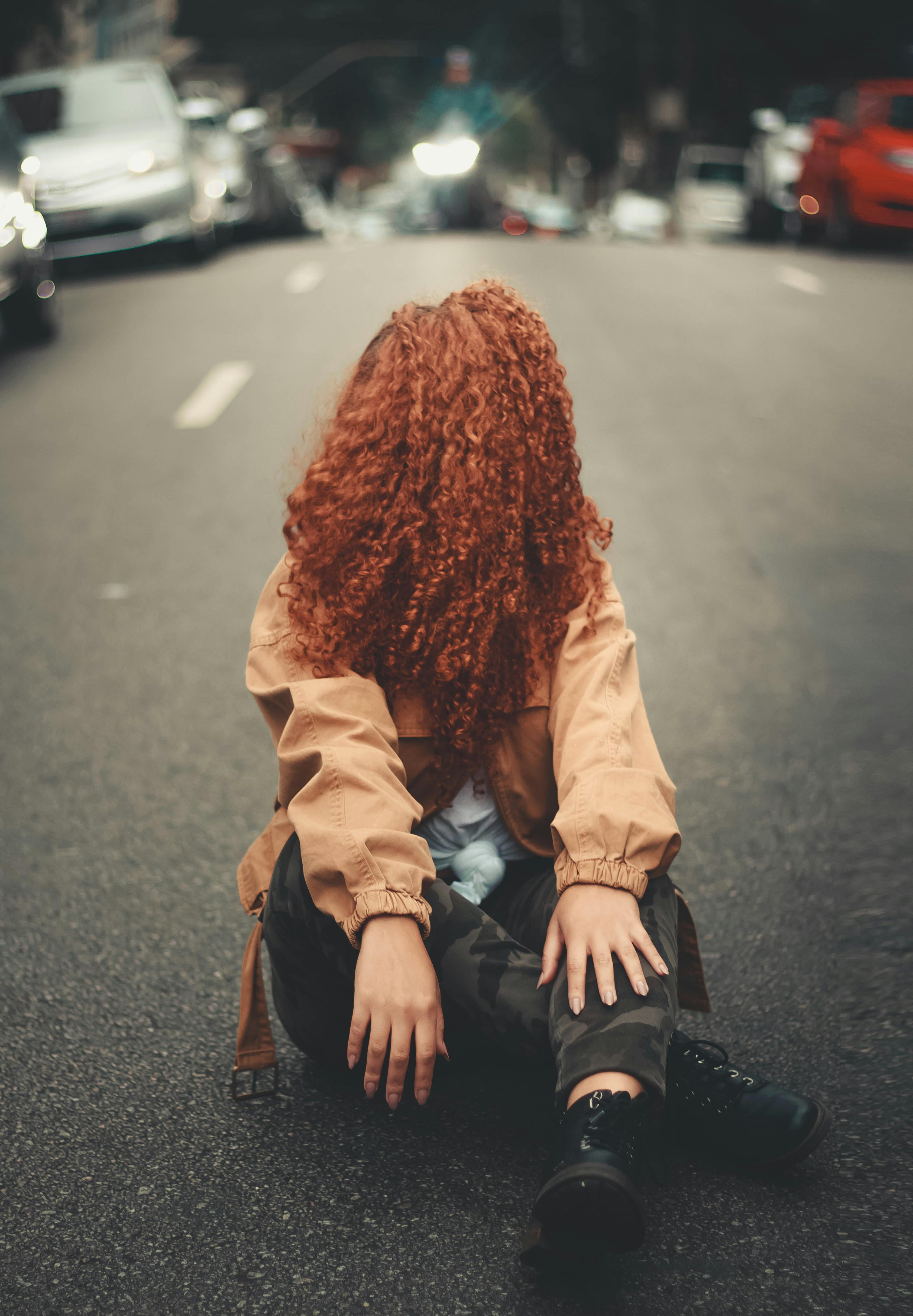 免费 坐在马路上的棕色夹克的女人 素材图片