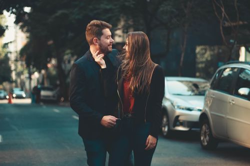 Free Happy couple in casual outfits caressing and looking at each other while standing on urban street in daylight Stock Photo