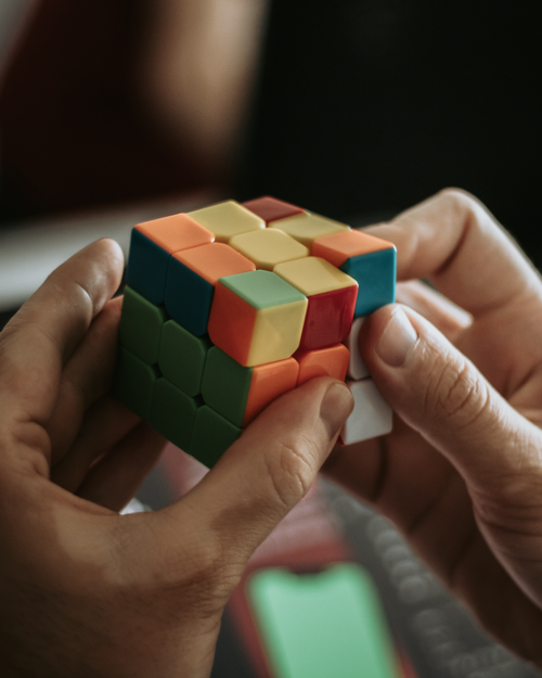 Free Close-up of hands solving a colorful Rubik's cube indoors. Stock Photo