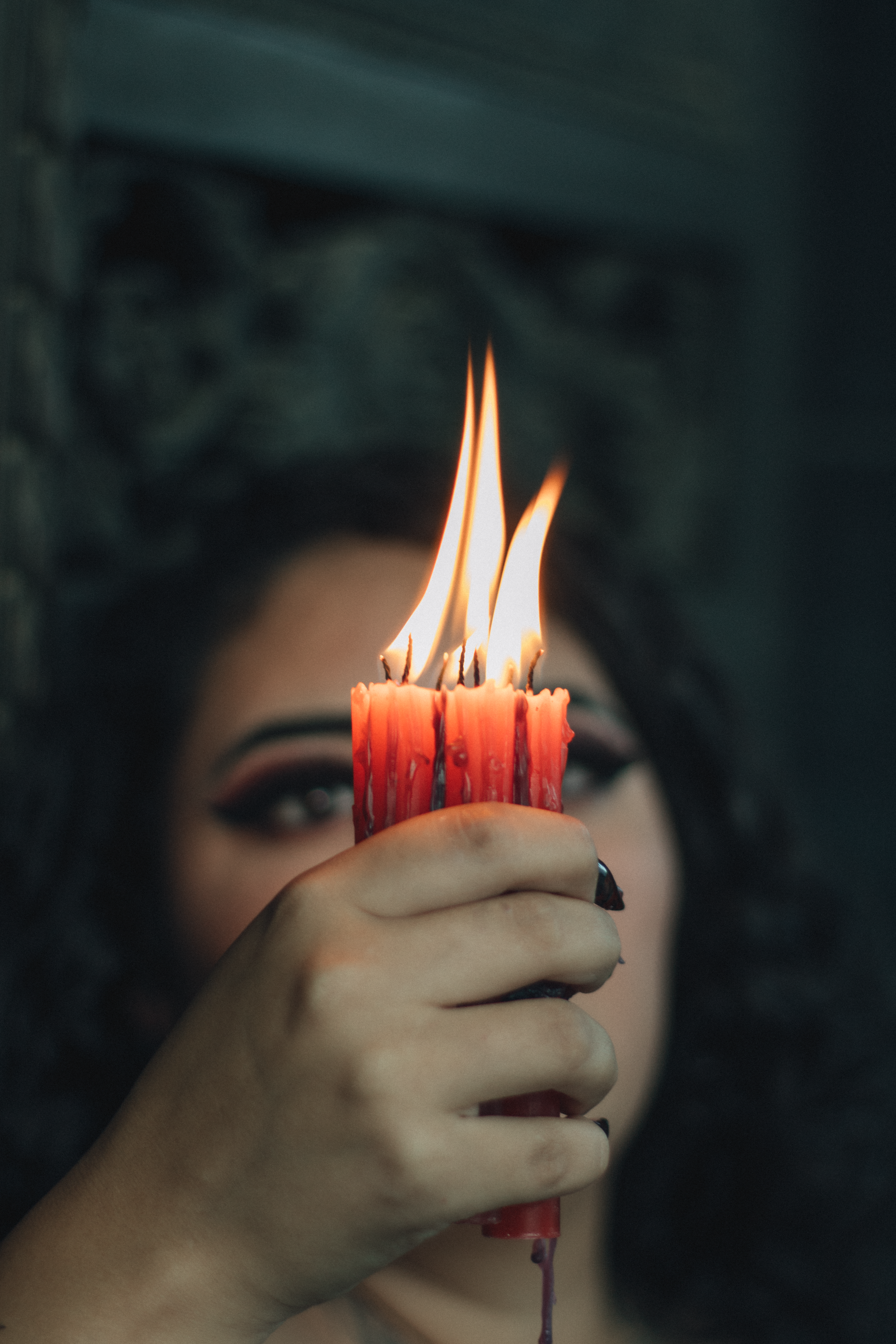A person holding a red candle with multiple wicks
