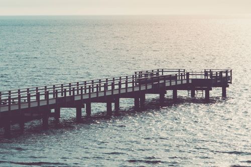 Free A tranquil pier extending into the ocean during sunset, creating a serene and peaceful atmosphere. Stock Photo