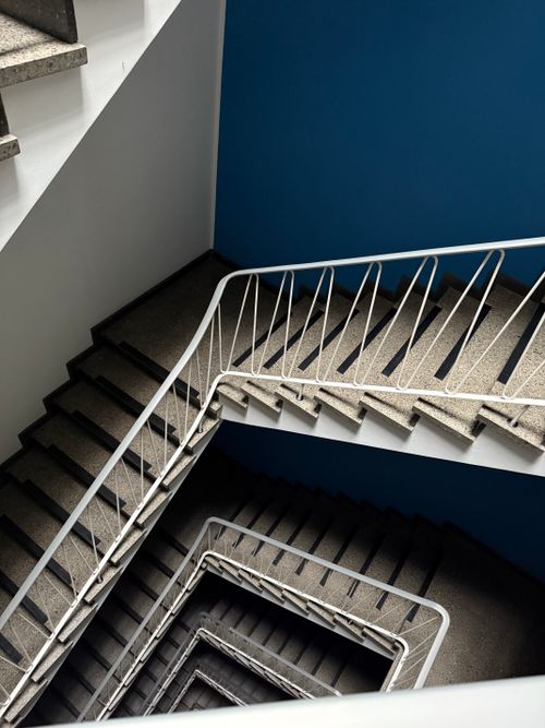Free Aerial view of a spiral staircase with a blue wall in a modern building. Stock Photo