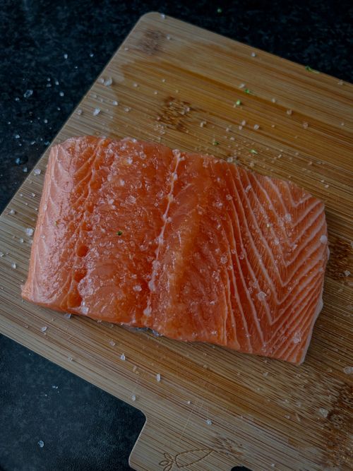 Free High-quality close-up of a fresh salmon fillet with salt on a bamboo cutting board. Stock Photo